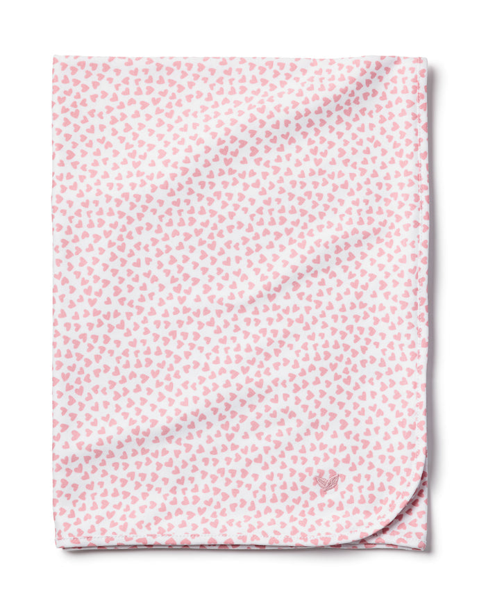 The Petite Plume Pima Baby Blanket in Sweethearts is a soft, white blanket made from luxurious Peruvian Pima Cotton. It features a pattern of small pink hearts, and a subtle outline of a small animal in one corner, adding both comfort and charm for your little one.