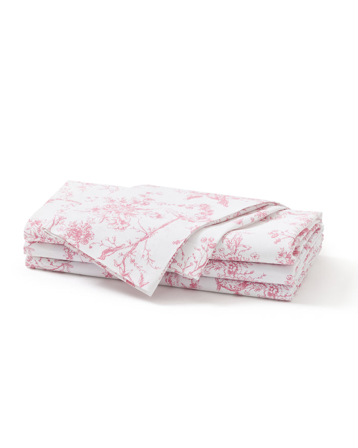 A neatly folded stack of Signature Twill Napkins in Pink Timeless Toile, featuring a delicate pink floral and branch pattern, displayed on a plain white background.