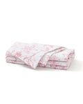A neatly folded stack of Signature Twill Napkins in Pink Timeless Toile, featuring a delicate pink floral and branch pattern, displayed on a plain white background.