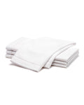 A neatly folded stack of Signature Twill Napkins in White by Petite Plume, placed on a white background. The napkins appear clean and crisp, emphasizing their soft texture and quality fabric.