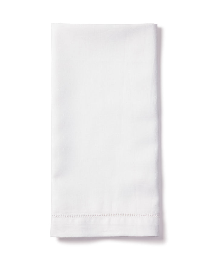 A neatly folded Signature Twill Napkin in White from Petite Plume rests against a white background. Made of 100% cotton, its perfect for enhancing a festive tablescape and features a simple hemmed edge.