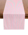 Elevate your festive tablescape with the Signature Twill Table Runner in Antique Red Ticking by Petite Plume, featuring red and white vertical stripes that complement your favorite table linens on a wooden surface.