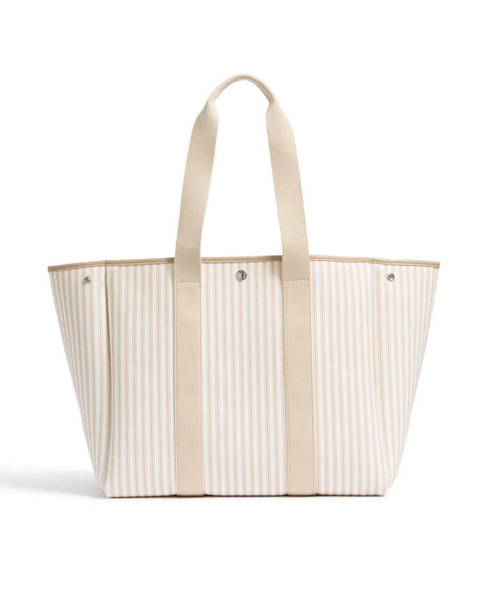 The Beckett Canvas Tote Bag in Camel Ticking features beige and white stripes, sturdy beige handles, and silver button details, displayed against a white background.