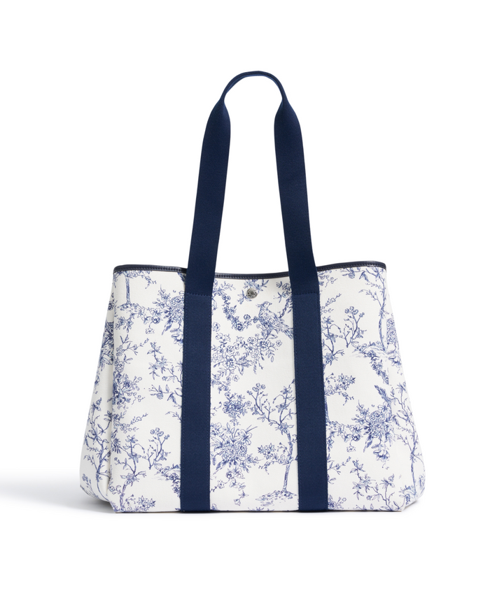 The Beckett Canvas Tote Bag in Timeless Toile features a blue nature print on white canvas and two long, wide navy handles, displayed on a white background.