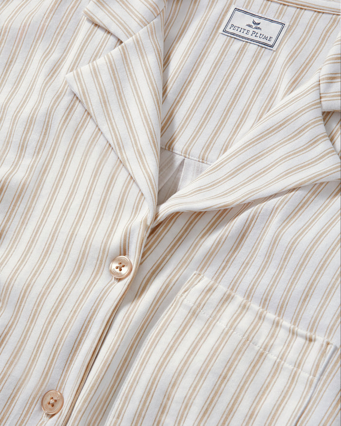The Olivia Pima Short Set in Camel Ticking features a two-piece pajama set with beige and white vertical stripes, including a button-up, collared long-sleeve shirt with a breast pocket, and matching relaxed-fit drawstring shorts.