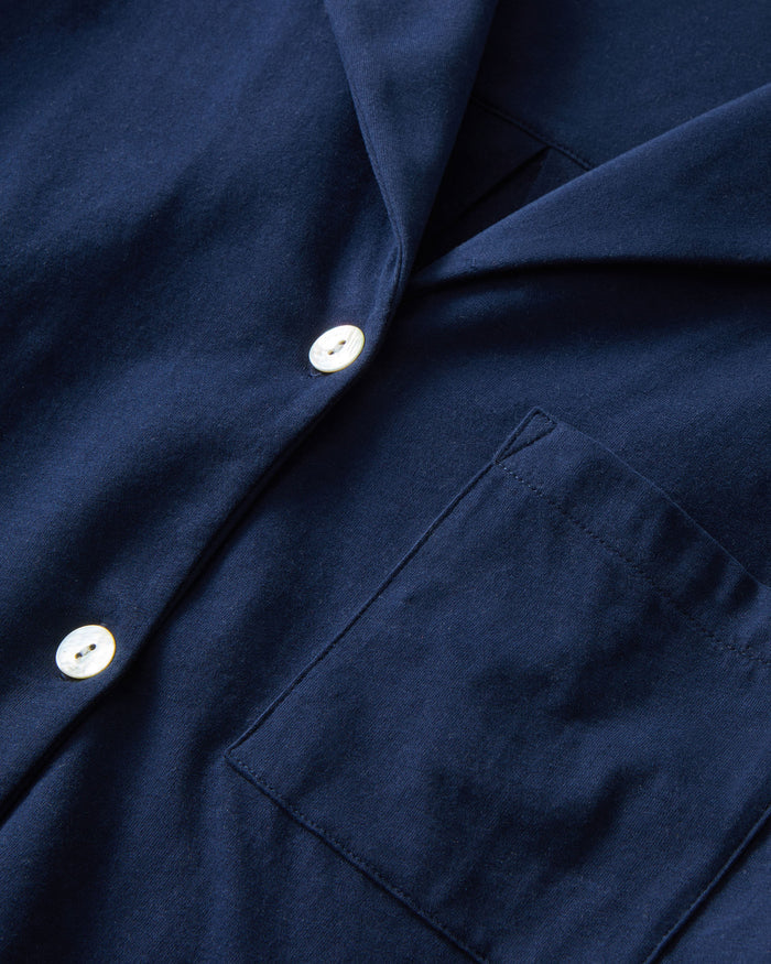 The Olivia Pima Short Set in Navy features a short-sleeve button-up top with a chest pocket and matching drawstring shorts, both displayed flat on a white background.