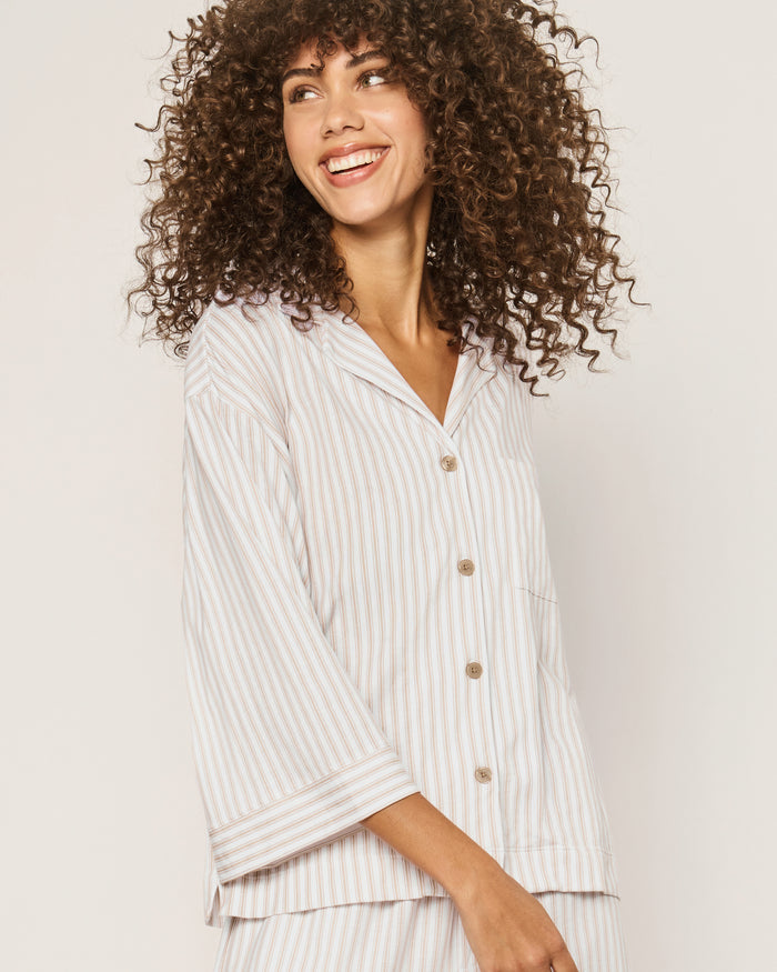 The Olivia Wide Leg Pima Pajama Set in Camel Ticking features light-colored, long-sleeve striped pajamas with brown buttons and matching drawstring pants, displayed flat on a white background.