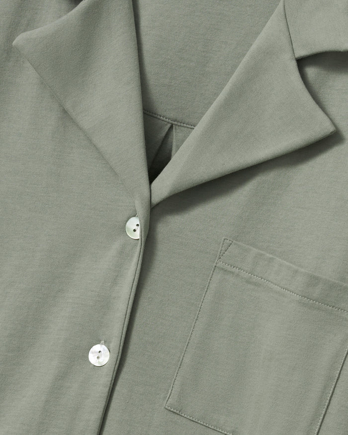 The Olivia Wide Leg Pima Pajama Set in Sage includes a button-up, collared top with a chest pocket and three-quarter sleeves, plus matching elastic waist wide-leg pants. Both pieces are neatly laid flat on a white background.