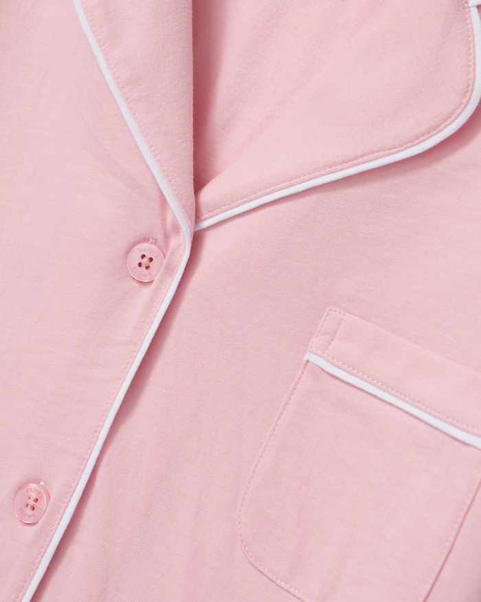 Close-up of The Poppy Lightweight Pima Short Set in Pink pajama top, featuring white piping, buttons, a collar, and a chest pocket. The fabric appears soft and lightweight.