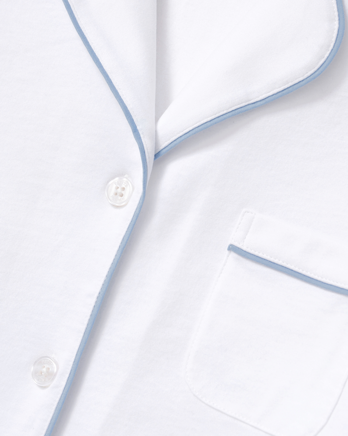 Close-up of The Poppy Pima Short Set in White with Periwinkle Piping, featuring white buttons and a chest pocket. The soft, smooth fabric is accented by delicate periwinkle piping.