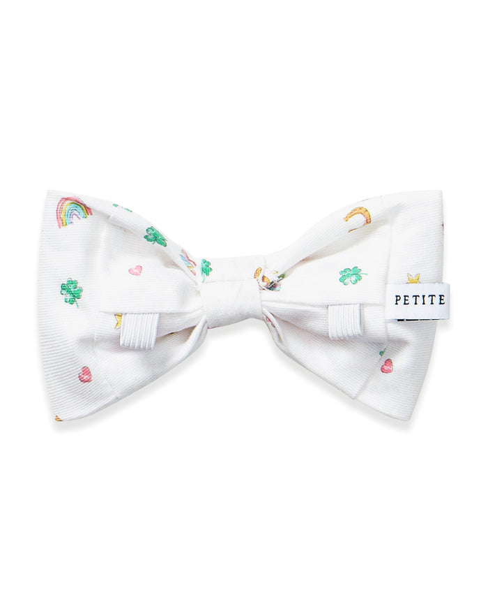The Twill Dog Bow Tie in Good Luck Charms is a white bow tie adorned with small, colorful rainbows, horseshoes, hearts, and stars scattered across the fabric.