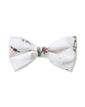 The Twill Dog Bow Tie in Holiday Town is a white bow tie adorned with playful, colorful illustrations of people skiing, sledding, and enjoying winter fun.