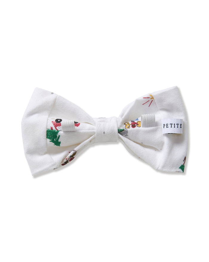 The Twill Dog Bow Tie in Holiday Town is a white bow tie adorned with playful, colorful illustrations of people skiing, sledding, and enjoying winter fun.