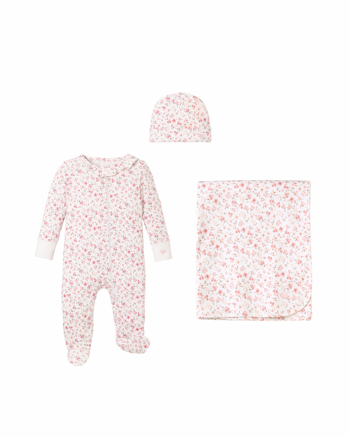 The Welcome Home Baby Set - Dorset Floral by Petite Plume includes a charming romper with full-length sleeves and legs, a matching hat, and cozy blanket, all featuring a pink floral design. The delightful set is beautifully presented on a plain white background.