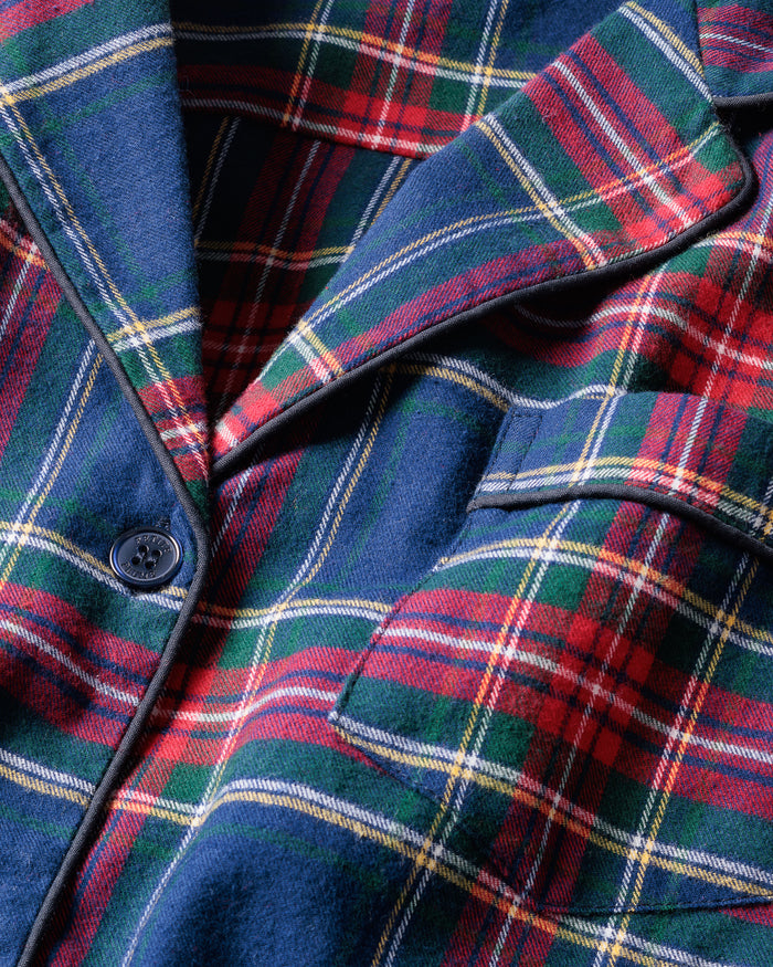 Close-up of Windsor Tartan fabric with red, green, and white stripes on navy by Petite Plume. The soft, brushed cotton texture resembles a classic pajama set with a button and lapel for added coziness.