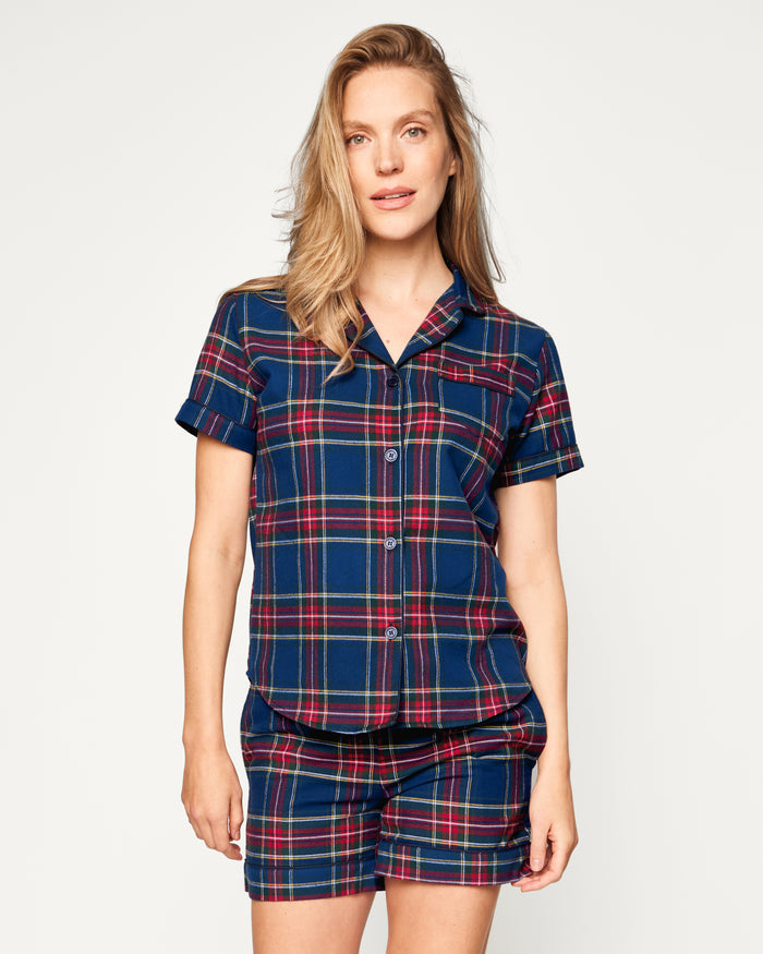 A close-up of Petite Plumes Womens Brushed Cotton Short Sleeve Short Set in Windsor Tartan showcases a blue, red, and green plaid fabric with a button emblem and contrasting piping on the pocket, epitomizing the elegance of luxury cotton sleepwear.