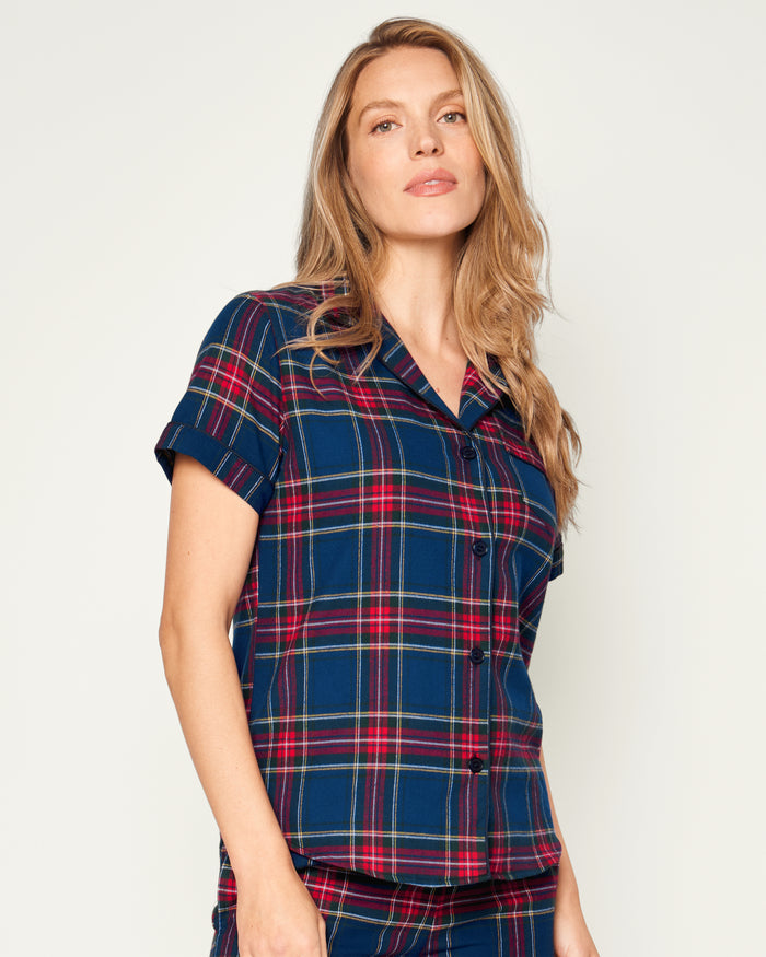 A close-up of Petite Plumes Womens Brushed Cotton Short Sleeve Short Set in Windsor Tartan showcases a blue, red, and green plaid fabric with a button emblem and contrasting piping on the pocket, epitomizing the elegance of luxury cotton sleepwear.