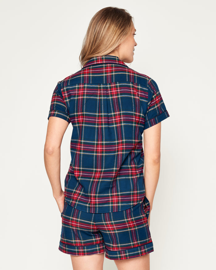 A close-up of Petite Plumes Womens Brushed Cotton Short Sleeve Short Set in Windsor Tartan showcases a blue, red, and green plaid fabric with a button emblem and contrasting piping on the pocket, epitomizing the elegance of luxury cotton sleepwear.