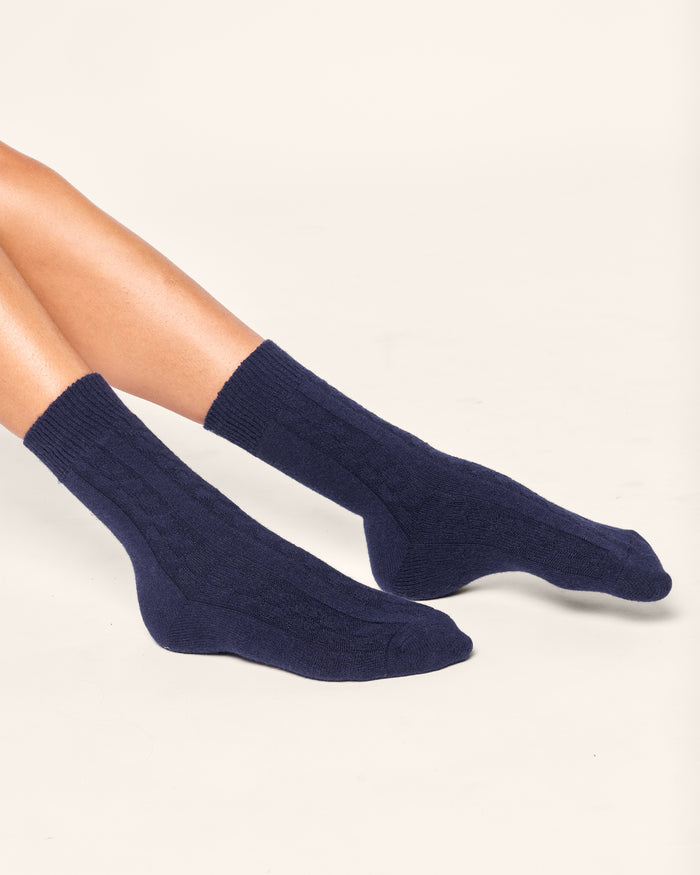 A person is wearing Petite Plumes Womens Cashmere Socks in Navy against a plain white background. These luxurious socks offer ribbed Grade A cashmere comfort, covering the ankles and part of the lower legs.