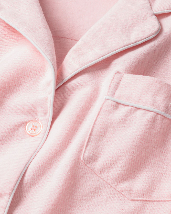 The Womens Flannel Pajama Set in Pink by Petite Plume features a classic design with white piping, a button-up front, collar, and pocket. It embodies timeless sleepwear style and ensures comfort with its soft 100% flannel fabric.