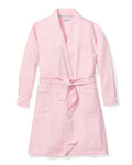 The Womens Flannel Robe in Pink by Petite Plume is a luxurious light pink bathrobe with long sleeves, two front pockets, a matching belt for the waist, and elegant white piping. Its crafted from high-quality cotton and laid flat against a white background for indulgent lounging.
