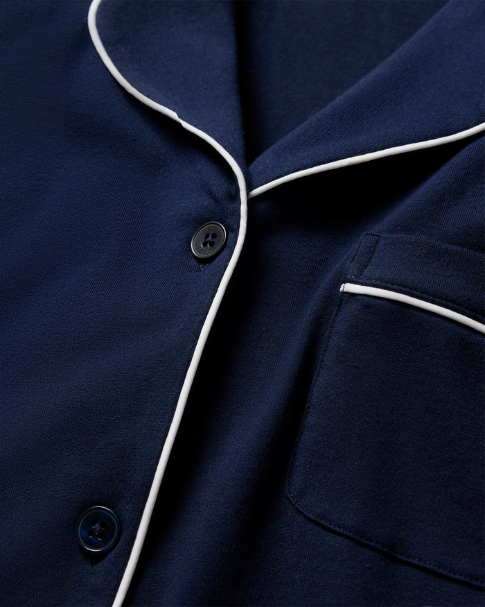 The Womens Pima Crop Set by Petite Plume features a navy blue top with white piping, crafted from luxurious Pima cotton. It includes black buttons and a pocket, showcasing a classic design in luxury sleepwear.