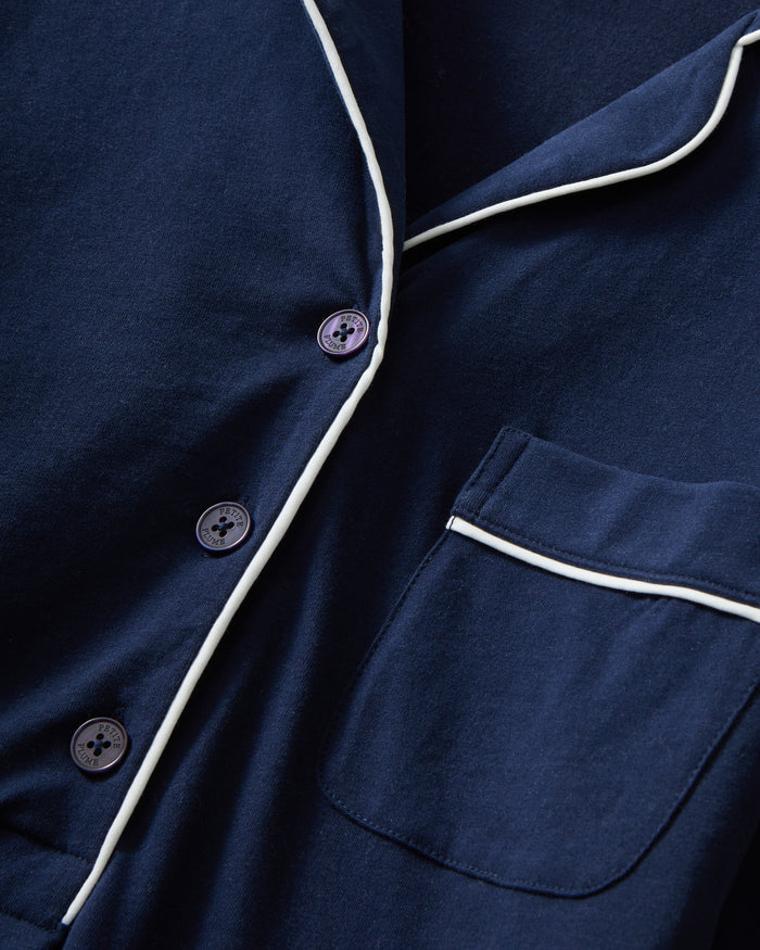 The Women's Pima Maternity Nightshirt in Navy features long sleeves, white piping on the collar, pocket, and cuffs, a chest pocket, button v-neckline, and a relaxed fit.