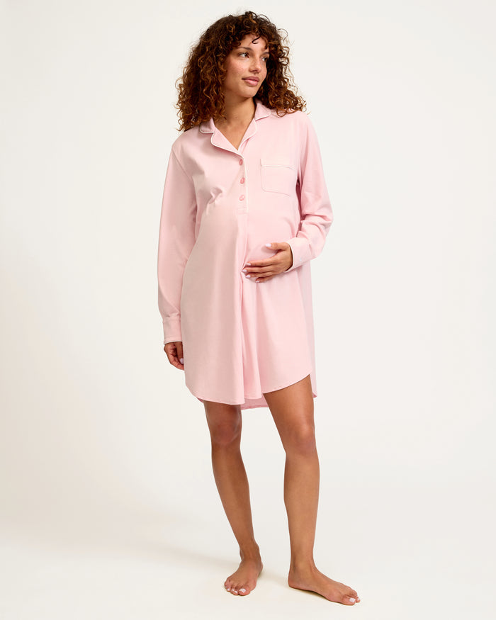The Women's Pima Maternity Nightshirt in Pink features long sleeves, white piping, a collar, front buttons, single chest pocket, and a curved hem in soft, comfortable fabric.