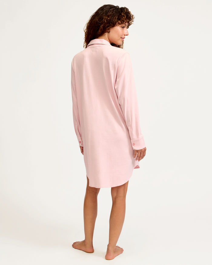 The Women's Pima Maternity Nightshirt in Pink features long sleeves, white piping, a collar, front buttons, single chest pocket, and a curved hem in soft, comfortable fabric.