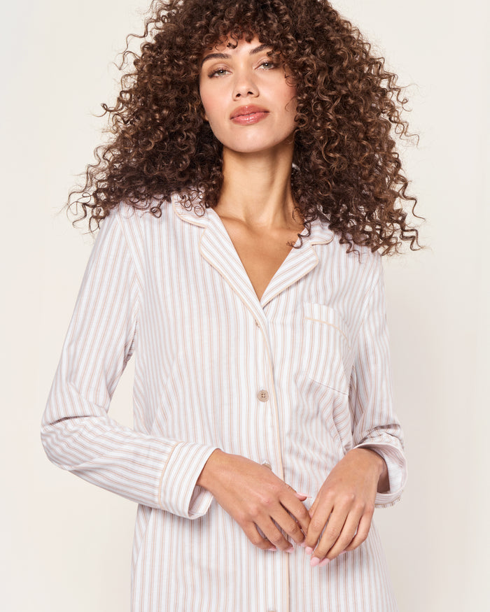 The Women's Pima Nightshirt in Camel Ticking features beige and white vertical stripes, long sleeves, a knee-length cut, button-down front, chest pocket, and collar; shown laid flat on a white background.
