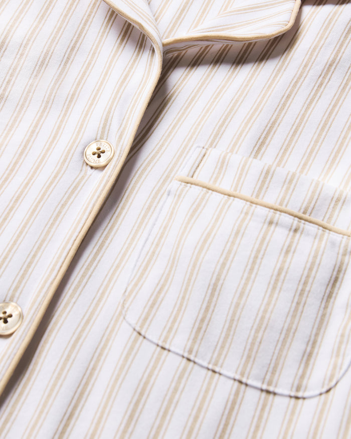 The Women's Pima Nightshirt in Camel Ticking features beige and white vertical stripes, long sleeves, a knee-length cut, button-down front, chest pocket, and collar; shown laid flat on a white background.