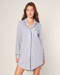 A person wearing the Womens Pima Nightshirt in Navy French Ticking by Petite Plume, made from exquisite Peruvian Pima cotton with blue and white stripes, stands against a light background with their hands relaxed at their sides.