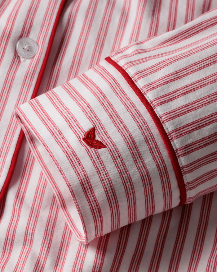 Close-up of Petite Plumes Womens Pima Pajama Set in Antique Red Ticking. Featuring luxurious red and white stripes, a Peruvian Pima cotton sleeve with a small embroidered heart above the cuff, white buttons, and elegant red piping on the cuff.