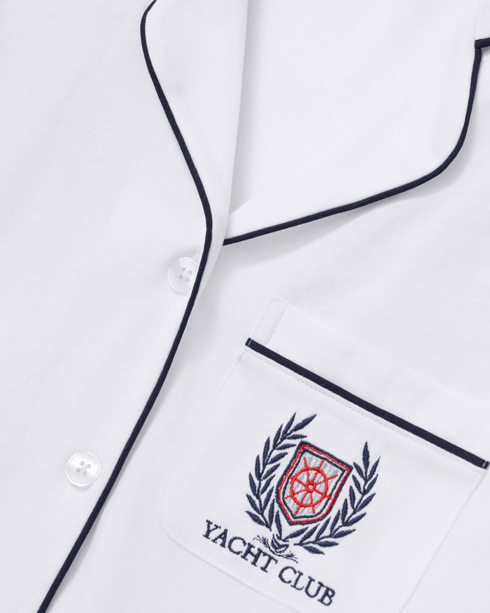 Close-up of the Women’s Pima Pajama Set in White with Yacht Club Embroidery, featuring black piping, white buttons, and a chest pocket adorned with an embroidered crest of laurel leaves and “YACHT CLUB” text.