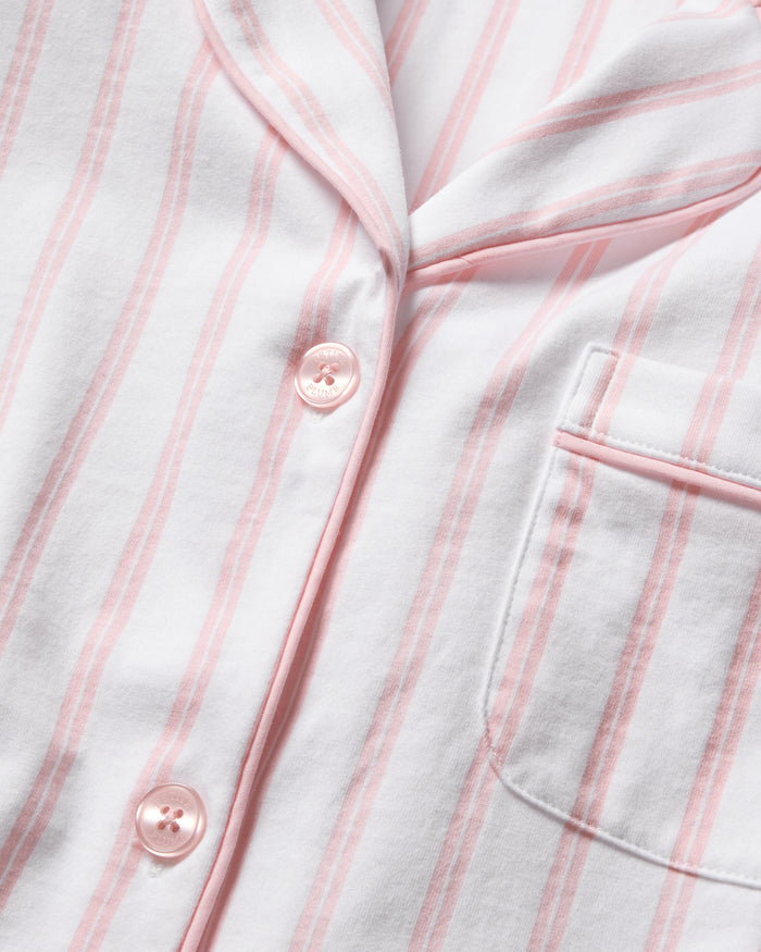 A close-up of Petite Plumes Womens Pima Pajama Short Set in Pink Stripe shows a white pajama shirt with pink stripes, crafted from soft Peruvian Pima cotton. It features pink buttons and a right chest pocket, embodying luxury pajamas.