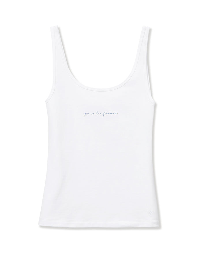 A woman with long blonde hair wears the Women's Pima Scoop Tank with "Pour Les Femmes" embroidery and beige drawstring pants, standing against a plain light background and smiling softly.