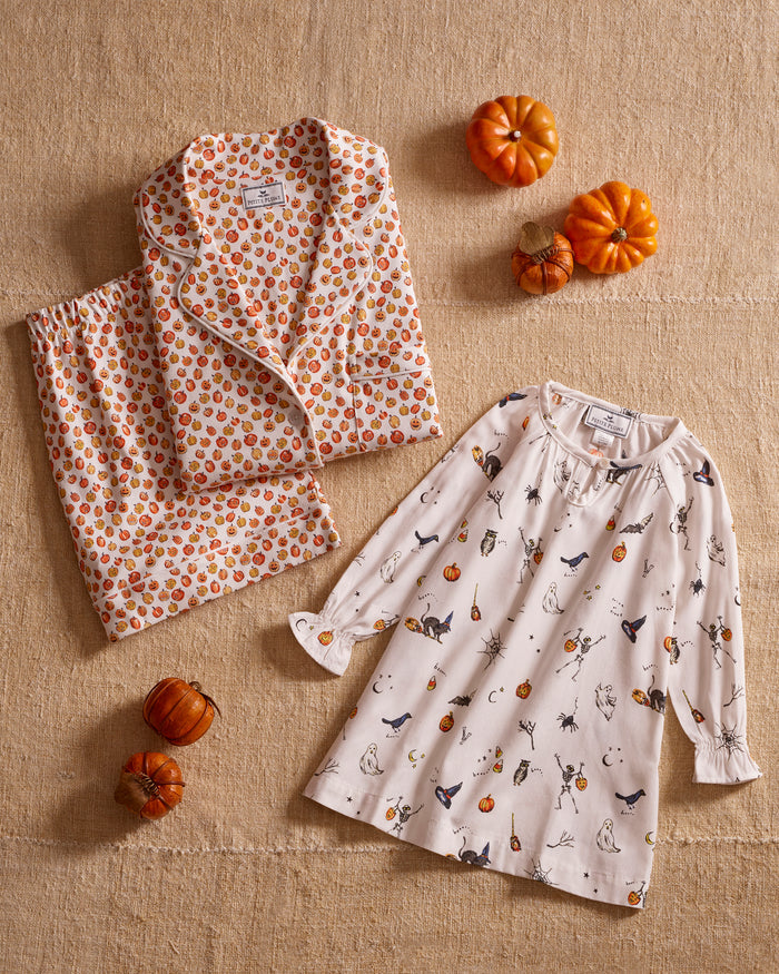 The Women's Pima Short Sleeve Short Set in Pumpkin Patch features a collared button-up top and matching shorts, both white with an orange and red fruit print and white piping on the edges.