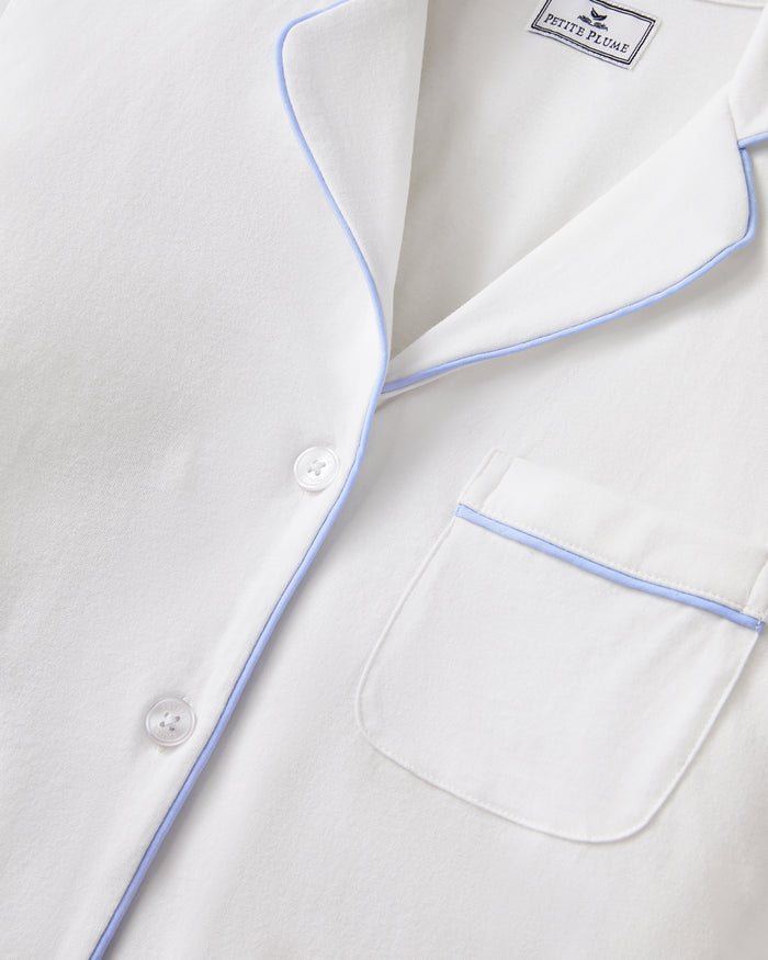 The Women's Pima Short Sleeve Short Set in White with Periwinkle Piping includes a collared button-up top with a chest pocket and matching shorts featuring an elastic waistband.