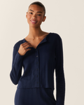 A person with pulled-back hair smiles at the camera against a plain light background, wearing the Women’s Pointelle Cardigan in Navy.