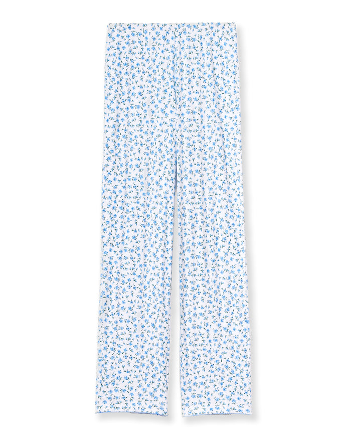 A woman stands barefoot against a plain background, wearing the Women's Pointelle Pant in Blue Floral paired with a matching short-sleeve pajama top featuring a white base and small blue floral print.