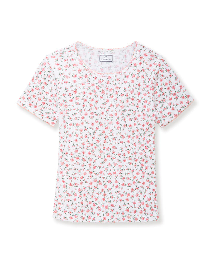 A woman with long curly hair wears the Women's Pointelle T-Shirt in Pink Floral, standing against a plain light background.