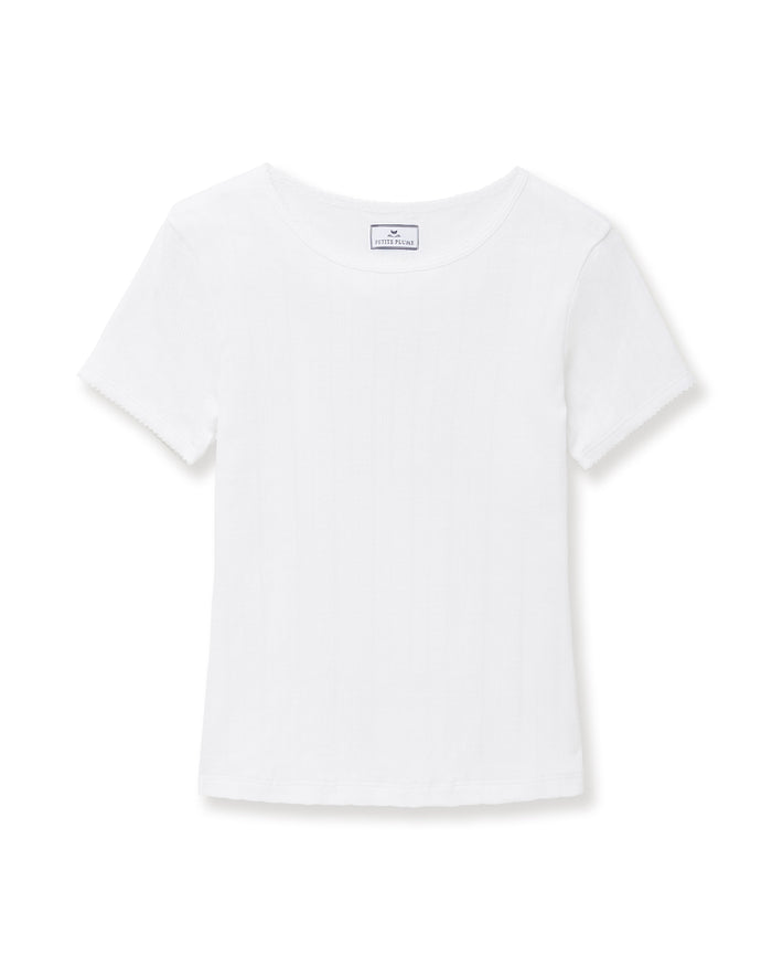 A woman with long brown hair wears the Women's Pointelle T-Shirt in White, standing against a plain light background and smiling gently at the camera.
