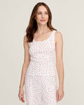 A woman with long brown hair smiles softly, wearing the Women's Pointelle Tank in Pink Floral with matching pants, standing against a plain light background.