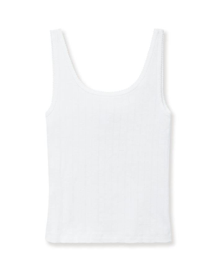 A woman with pulled-back hair wears the Women's Pointelle Tank in White and matching bottoms, standing against a plain light background and smiling softly at the camera.