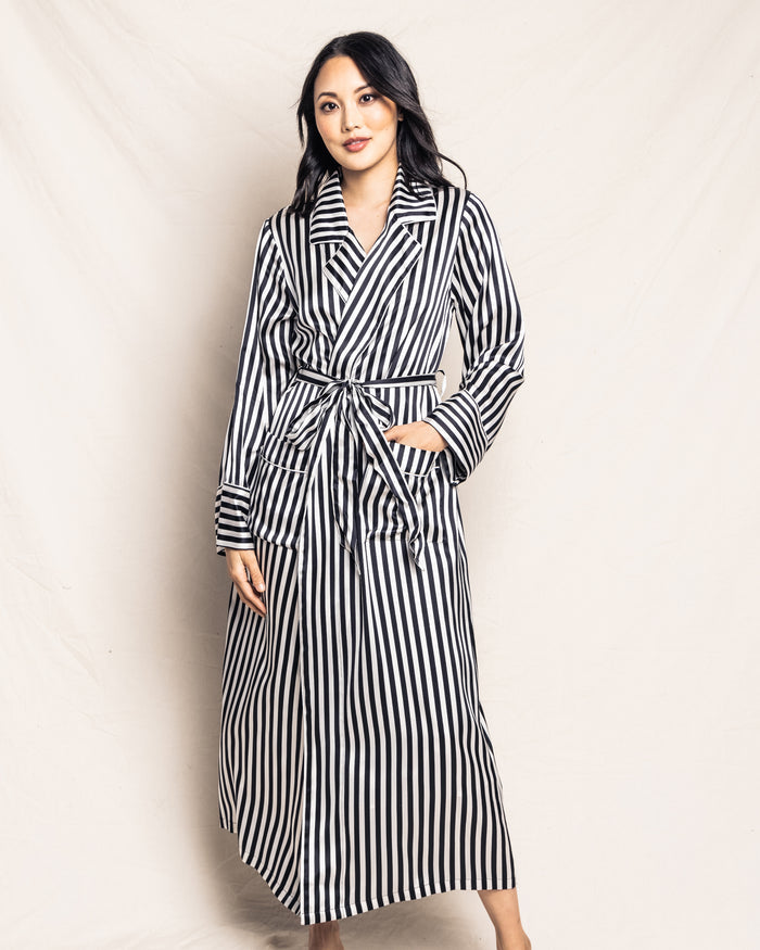 A person in a Petite Plume Womens Silk Long Robe in Bengal Stripe poses confidently against a plain backdrop, their long dark hair and expression capturing the bold flair of the Cabaret Collection.