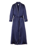The Womens Silk Long Robe in Navy by Petite Plume epitomizes luxury sleepwear with its white piping, shawl collar, long sleeves, matching waist belt, and two front pockets adorned with white trim for added sophistication.