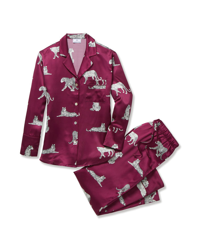 The Women's Silk Pajama Set in Merlot Panthère features a silky, deep magenta button-up shirt and pants adorned with an all-over white illustrated leopard print.