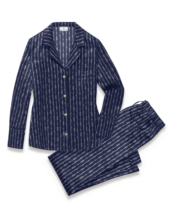 Women’s Silk Pajama Set in Nautical Knots: a navy blue silk pajama set with white vertical stripes, including a button-up long-sleeve top and matching drawstring waist pants.