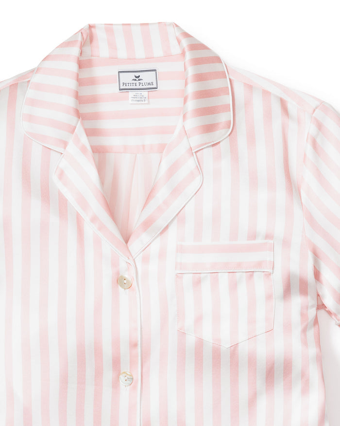 A close-up shows the Womens Silk Pajama Short Set in Pink Stripe by Petite Plume, featuring a collared top with a chest pocket and pearl-colored buttons. Made from Mulberry silk, the fabric looks silky and luxurious.