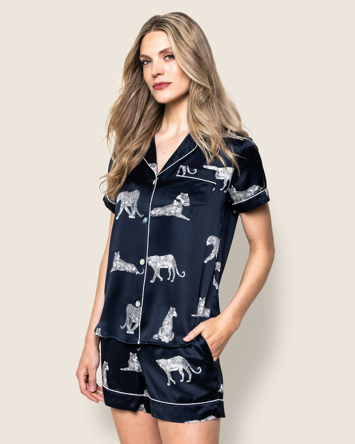 A women's silk short set in navy with a white animal print, featuring a button-up top and matching shorts with a elastic waistband.